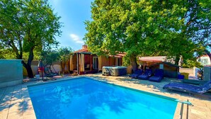 A swimming pool with lounge chairs and a hot tub, surrounded by trees and covered structures. - Gorgeous home in Pula with WiFi (Pula)