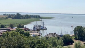 Un port de plaisance avec des bateaux amarrés, un ciel dégagé et une côte lointaine.