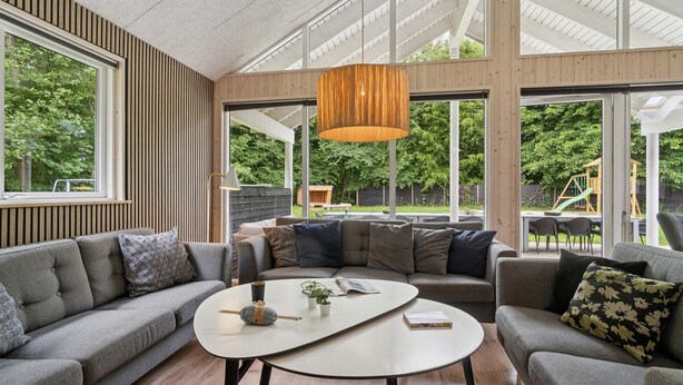 Una sala de estar moderna con un ventanal grande, techo de madera y una mesa de centro.