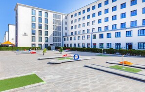 A modern building with multiple floors and a courtyard with geometric sculptures and greenery.