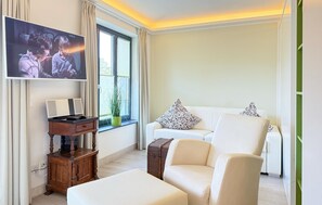 A modern living room with a sofa, a coffee table, a TV, a wooden side table, and a potted plant.