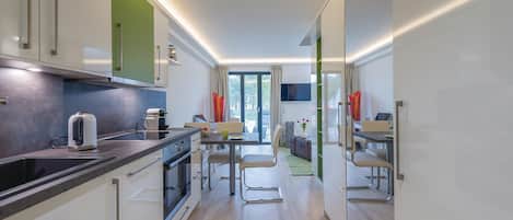 A modern kitchen with a dining area, a TV, and a view of the outdoors.