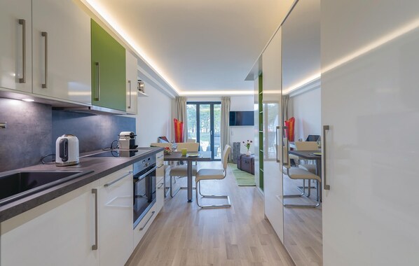 A modern kitchen with a dining area, a TV, and a view of the outdoors.