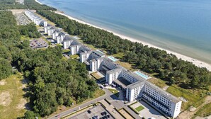 Ein Küstenhotel mit mehreren Gebäuden, einem Strand und einem Parkplatz.