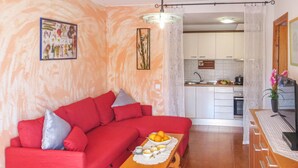 A living room with a red sofa, a coffee table with fruit, and a kitchen in the background. - Amazing apartment in Torrevieja with WiFi (Torrevieja)