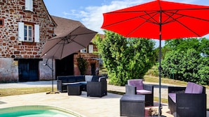A patio with outdoor furniture, a swimming pool, and a stone building in the background. - Gorgeous home in Badefols D'Ans (Badefols D'Ans)