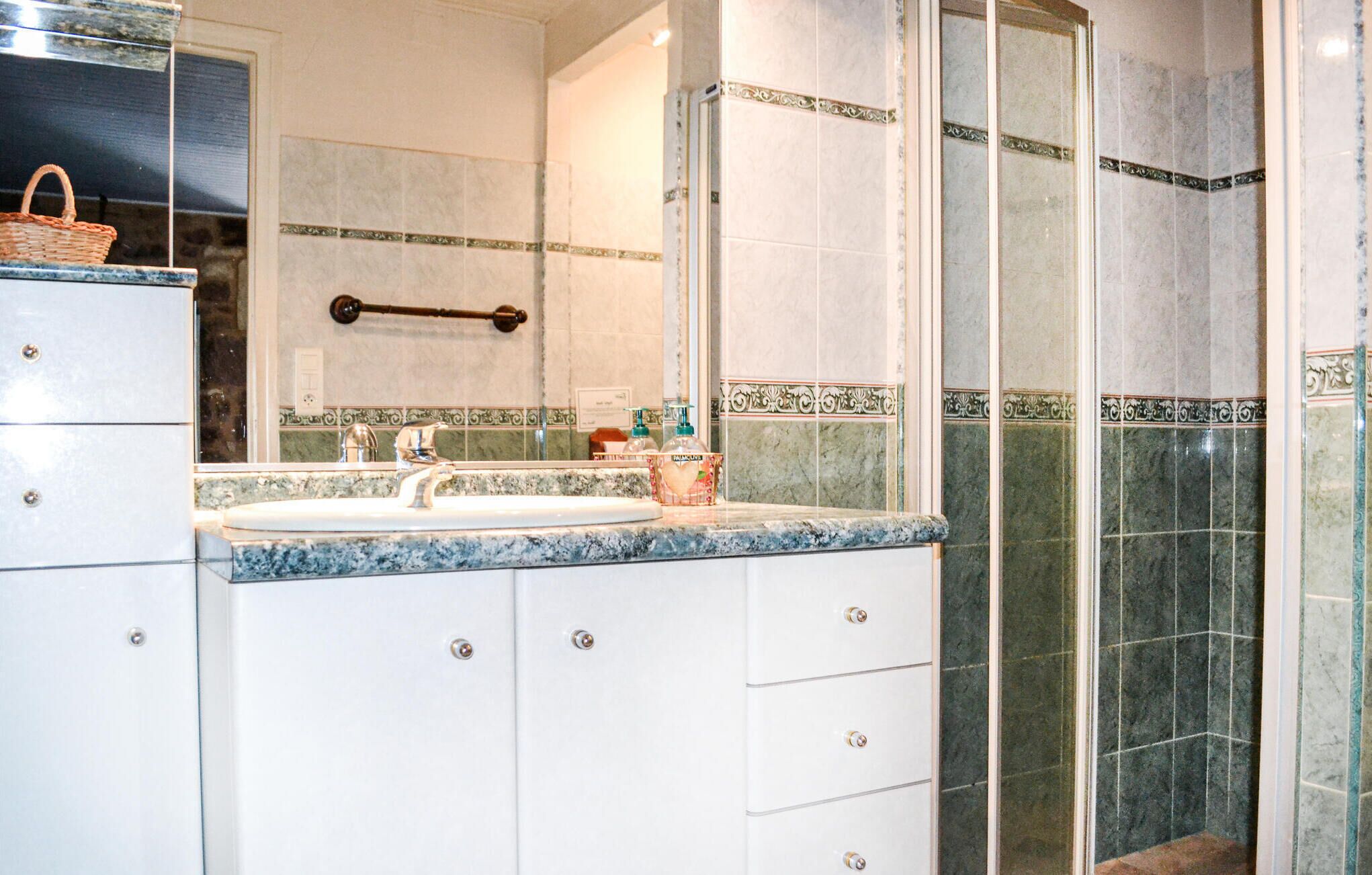A bathroom with a marble sink, a towel rack, and a shower area.