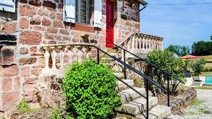 A stone building with a red door, a staircase with a balustrade, and a small garden area. - Gorgeous home in Badefols D'Ans (Badefols D'Ans)
