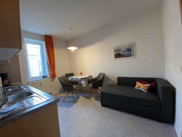 A compact living space with a kitchenette, dining area, and a sofa.