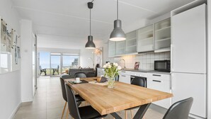 A modern kitchen with white cabinets, a wooden dining table, black chairs, and pendant lights. - 3 bedroom gorgeous home in Assens (Assens)
