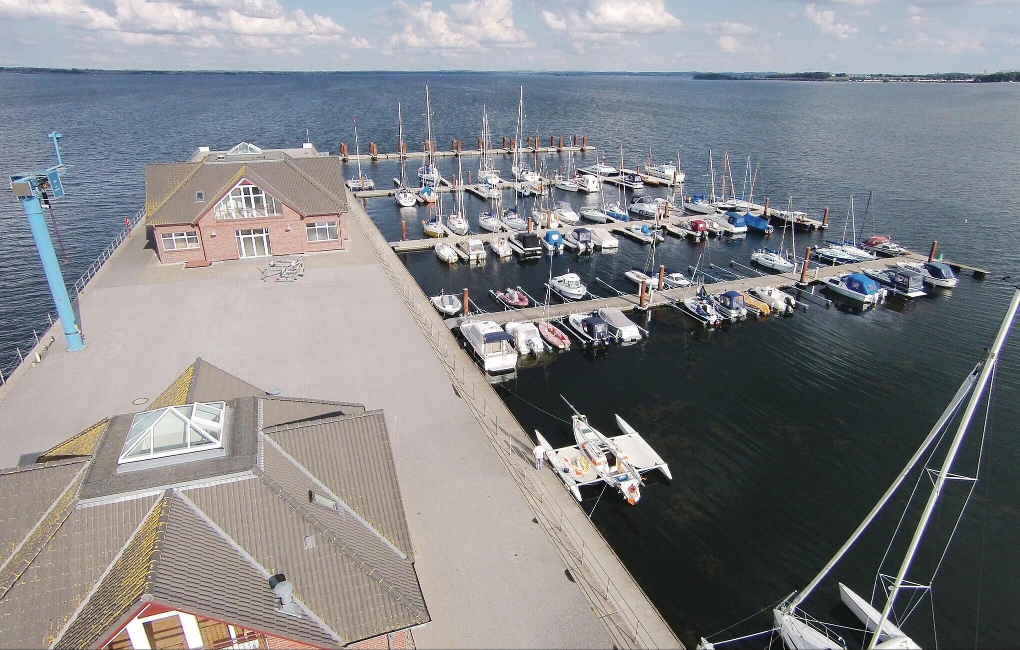 A marina with boats docked, a building with a sloped roof, and a clear sky.