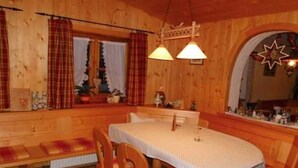 A wooden interior with a table and benches, a window with curtains, and a star-shaped decoration on the wall.