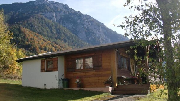 A wooden cabin with a porch, a small garden, and a mountain backdrop. - Ferienalm, Germany (Ruhpolding)