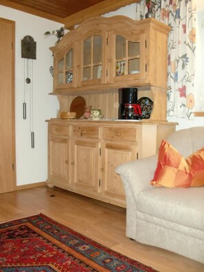 A living room with a wooden cabinet, a coffee maker, a clock, and a patterned rug. - Ferienalm, Germany (Ruhpolding)