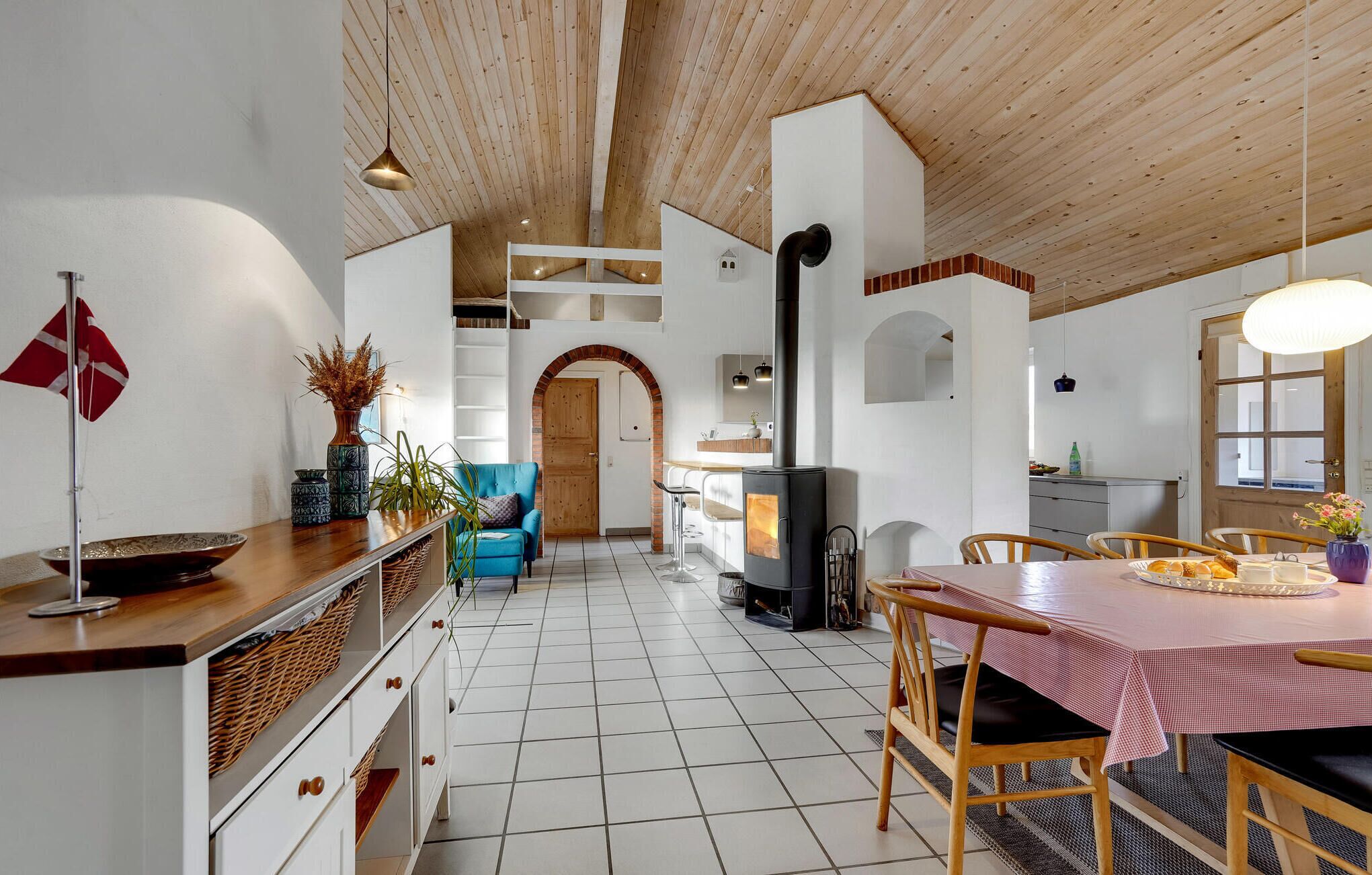 Una cocina amplia con una isla central, un comedor con mesa y sillas, y una chimenea visible.