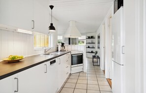 Une cuisine moderne avec des meubles blancs, un plan de travail noir et un four encastré.
