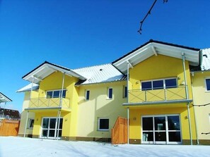 A yellow multi-story building with large windows and a flat roof.