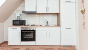 A modern kitchen with white cabinets, a microwave, a stove, and a sink.