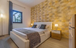 A bedroom with a bed, nightstands, a lamp, and a window.
