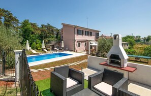 A poolside area with a pool, lounge chairs, and a barbecue grill.
