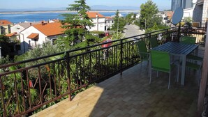 Ein Balkon mit Blick auf eine Küstenstadt, mit Fliesenboden und Metallgeländer.