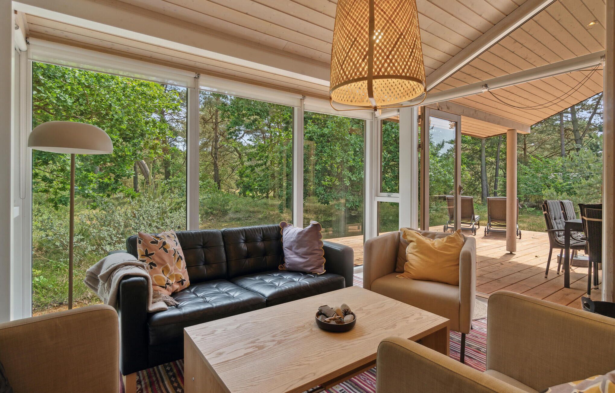 Un espace intérieur spacieux, doté d’une grande fenêtre, d’un canapé confortable, d’une table en bois et d’un luminaire suspendu.