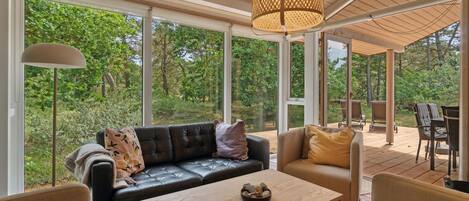 Un espace intérieur spacieux, doté d’une grande fenêtre, d’un canapé confortable, d’une table en bois et d’un luminaire suspendu.