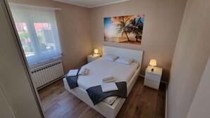 Une chambre avec un grand lit, deux tables de chevet avec des lampes, une fenêtre donnant sur un beau paysage et un tableau accroché au mur.