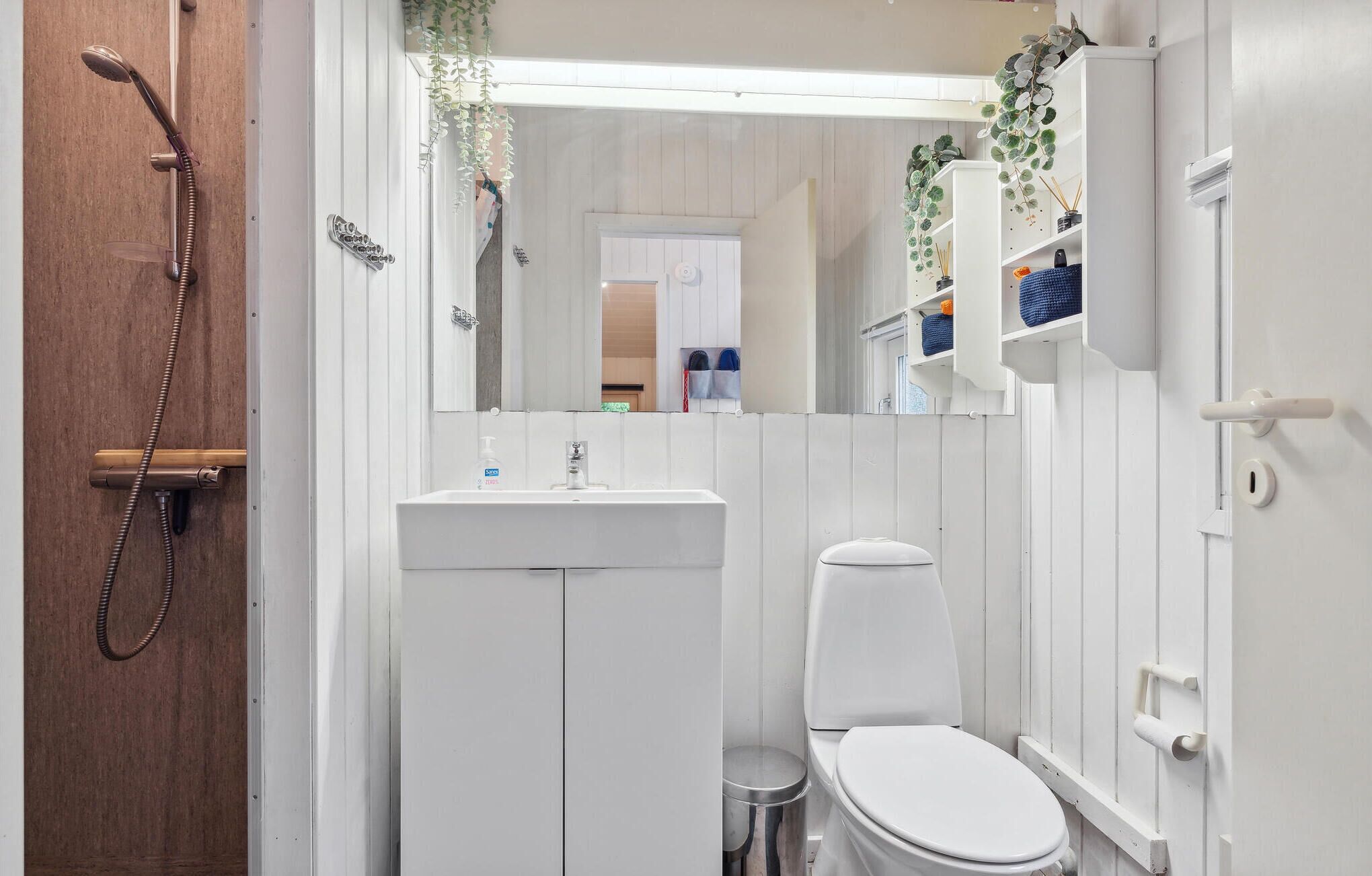Et lille badeværelse med bruser, toilet og håndvask.