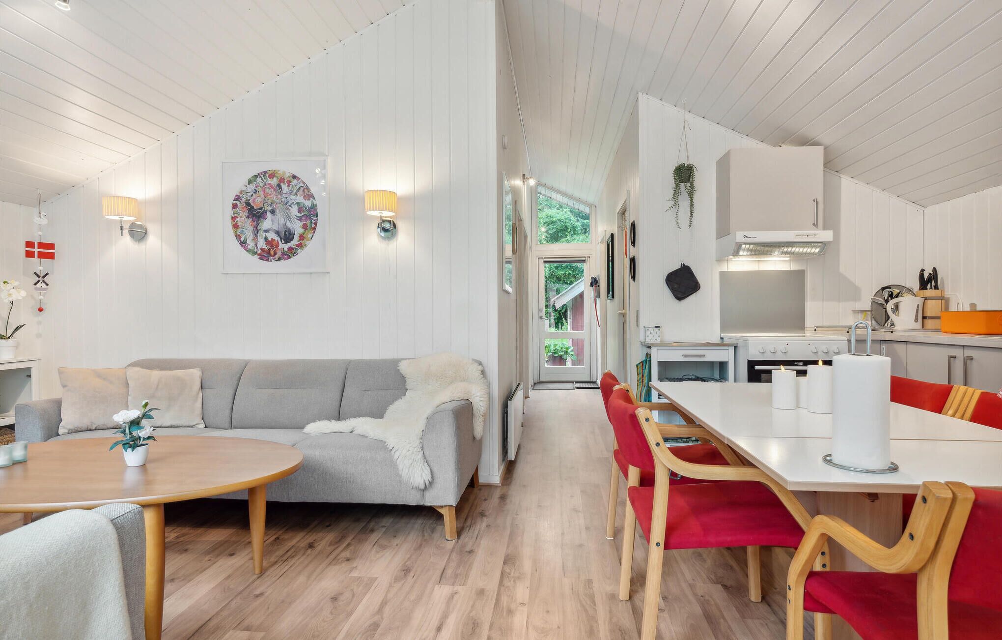 Une cuisine moderne avec des meubles blancs, une cuisinière et un coin repas comprenant une table et des chaises.