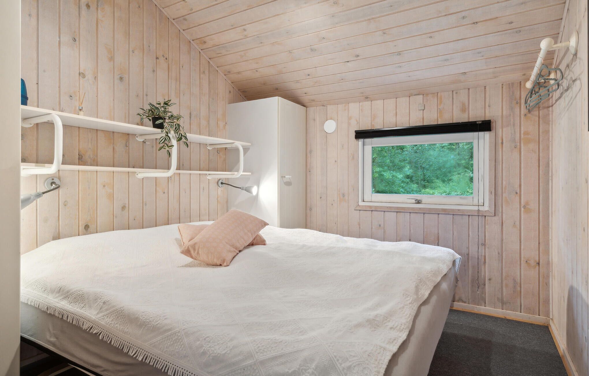 Une chambre à coucher avec un lit, une fenêtre et des murs en bois.
