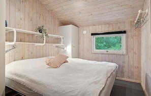 Une chambre à coucher avec un lit, une fenêtre et des murs en bois.