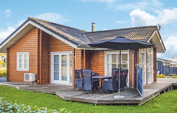 Eine Holzhütte mit einer Terrasse, Sitzgelegenheiten im Freien und einem Schornstein.