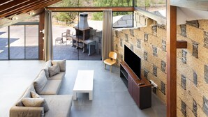 A modern living room with a sectional sofa, a white coffee table, a TV, and a stone fireplace. - Casa Rural Altos Cruz de Tea (Granadilla de Abona)