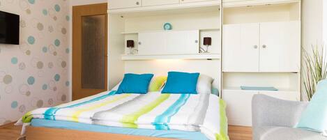 A bedroom with a bed, a bedside table, a chair, and a wardrobe.