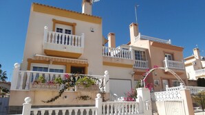 Un immeuble à plusieurs étages doté de balcons, d’une entrée sécurisée et agrémenté de plantes décoratives.