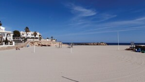 Ein Strand mit einem weißen Gebäude, Palmen und einem klaren Himmel.