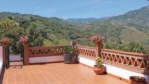A terrace with terracotta tiles, potted plants, and a view of a hilly landscape. - Lovely home in Frigiliana (Frigiliana)