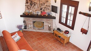 A living room with a brick fireplace, a wooden coffee table, and a sofa. - Lovely home in Frigiliana (Frigiliana)