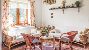 A cozy living room with wicker furniture, a white sofa, and a coffee table with a vase of flowers.