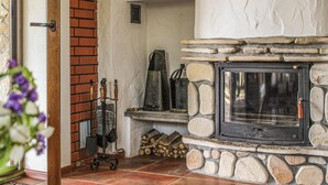 A stone fireplace with a metal door, a brick wall, and a wooden bench.