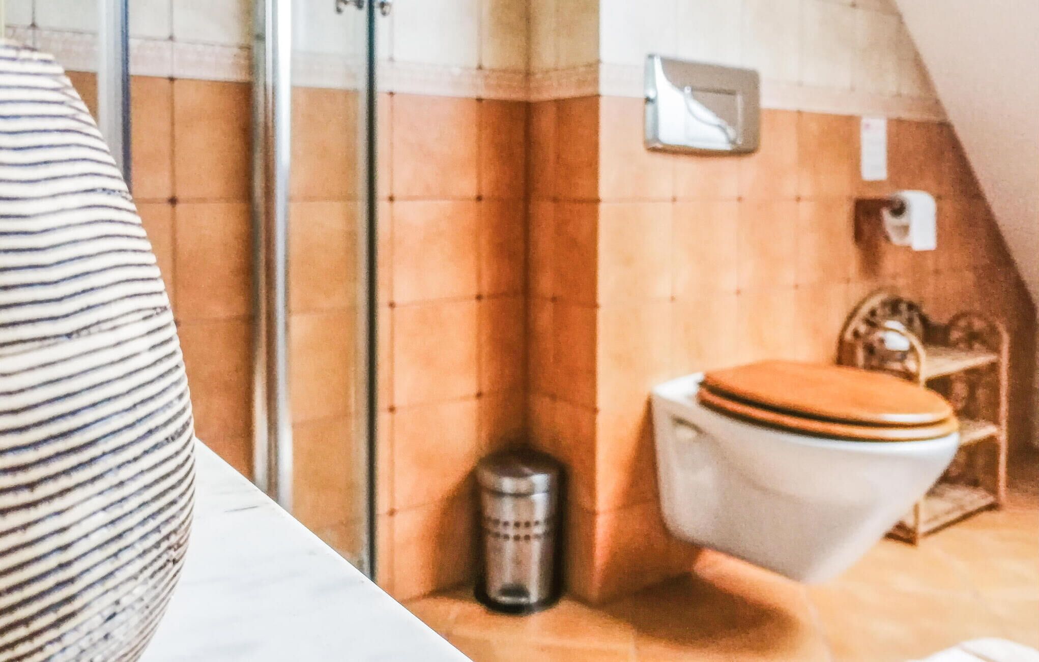 Een badkamer met toilet, prullenbak en handdoekhouder.