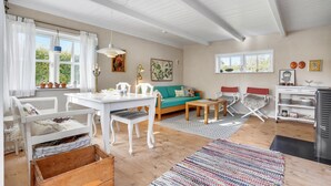 A bright living room with a white sofa, a wooden dining table, and a kitchen area with a stove. - 1 bedroom nice home in Knebel (Knebel)