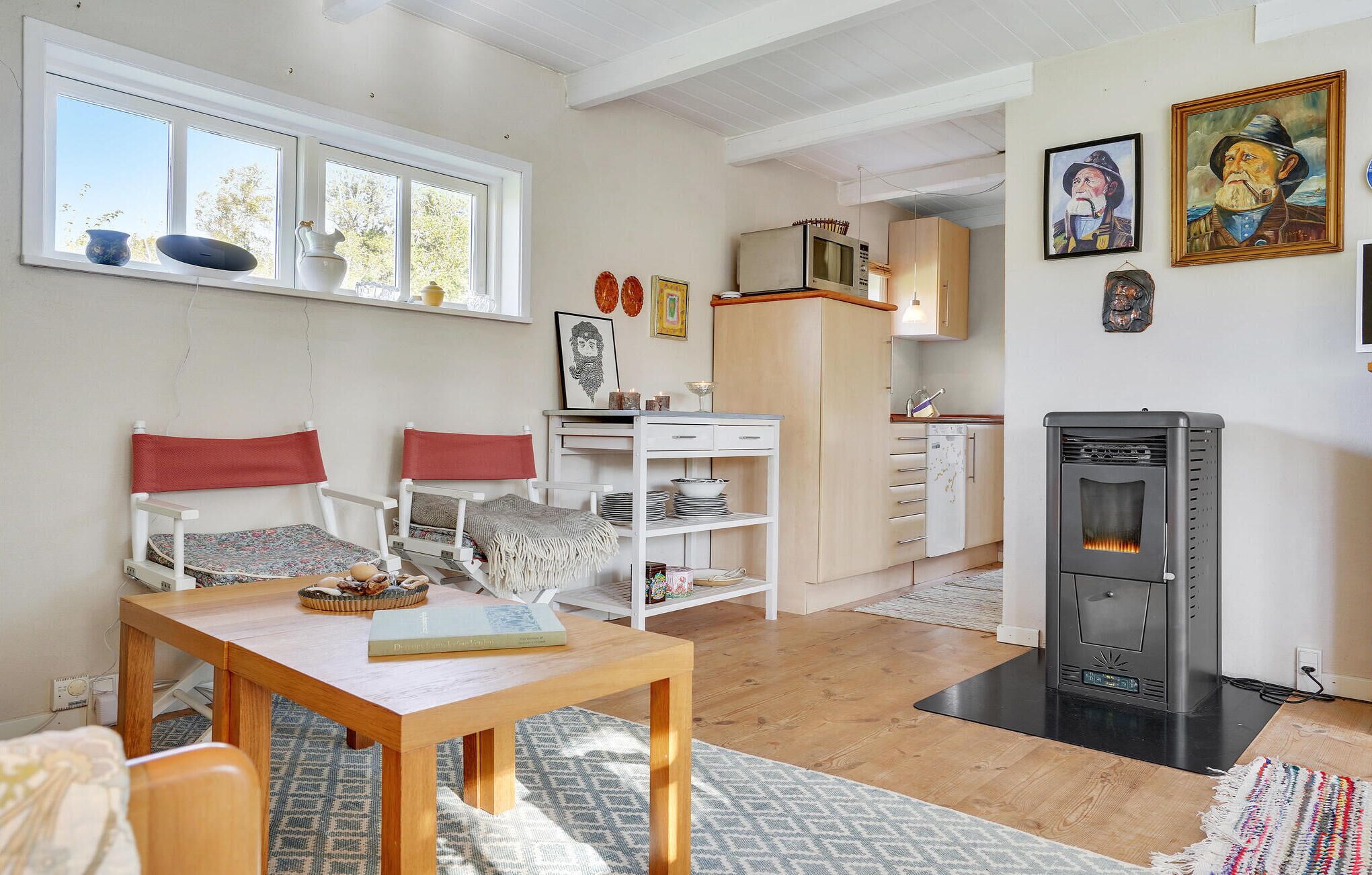 A cozy living room with a wooden table, two chairs, a bookshelf, and a fireplace.