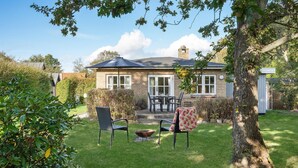 A two-story house with a patio area, a dining table with chairs, and a small garden. - 1 bedroom nice home in Knebel (Knebel)