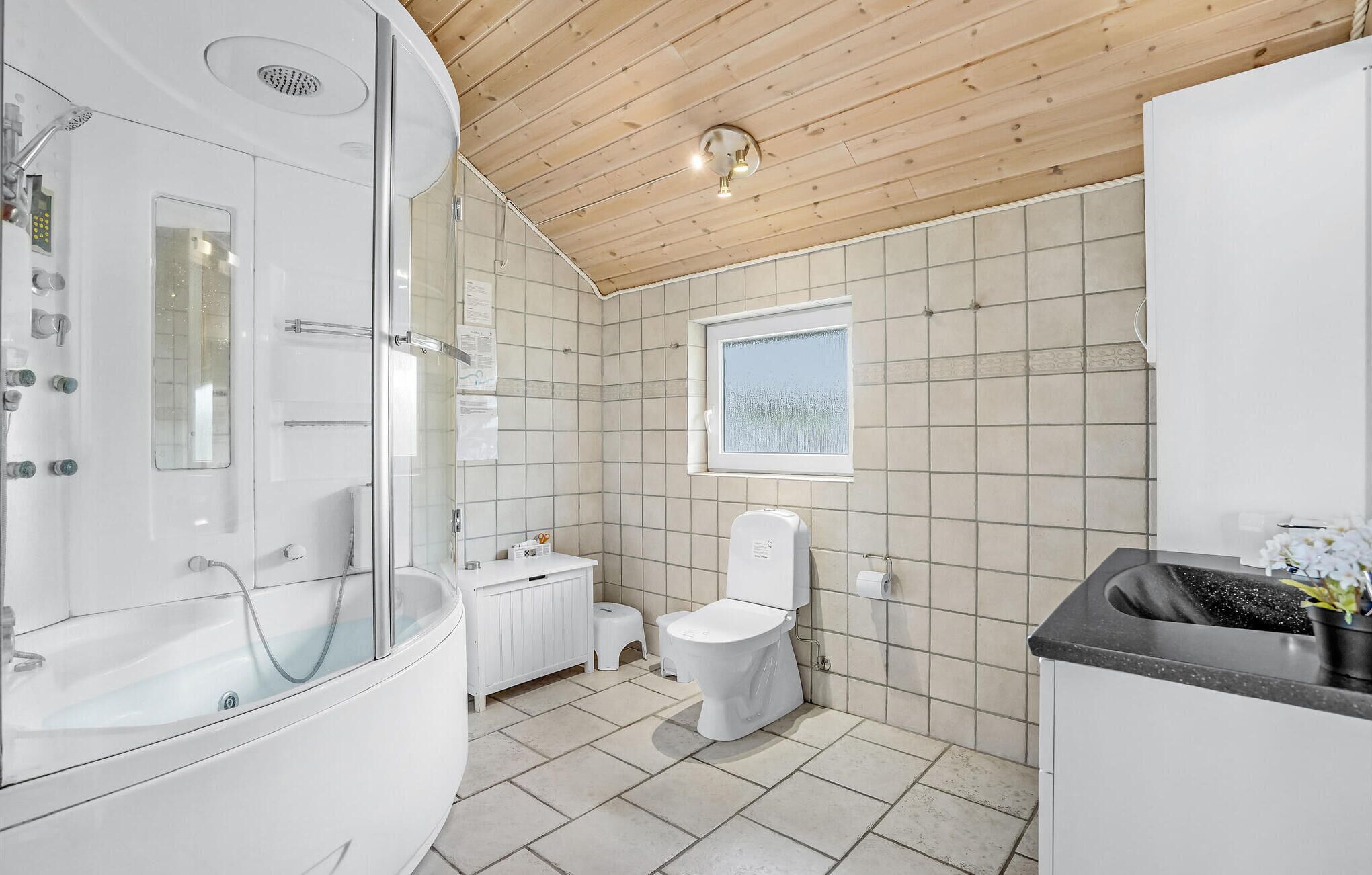 Une salle de bain moderne avec une douche à parois de verre, des toilettes, un lavabo et une fenêtre.