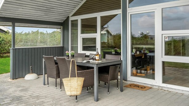 An outdoor patio with a table and chairs, a wicker basket, and a doormat. - Stunning home in Tarm with sauna (Tarm)