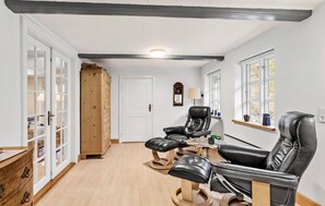 Relax in a spacious room with a clean design, featuring a large mirror, wooden wardrobe, and comfortable leather chairs.