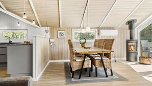 A modern kitchen with a central island, a dining area with wicker chairs, and a wood-paneled ceiling. - Beautiful home in Rømø with kitchen (Rømø)