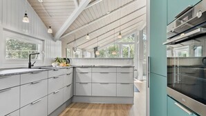 A modern kitchen with grey cabinets, a black faucet, and a teal oven. - Beautiful home in Rømø with kitchen (Rømø)